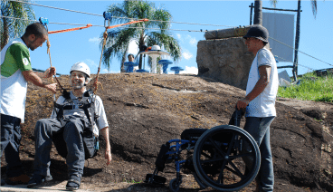 Usuário de cadeira de rodas sendo preparado para fazer a tirolesa do pânico no hotel fazenda parque dos sonhos